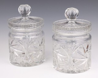 A pair of cylindrical cut glass biscuit barrels, with associated lids, 18cm x 16cm 