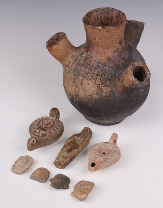 A Roman earthenware lamp decorated with a mask 10cm, a ditto with geometric decoration 9cm, a standing figure 10cm, 4 fragments and a similar incised 4 spout vase with incised geometric decoration 19cm 