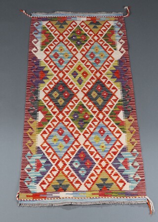 A tan, green, white and black ground Chobi Kilim runner with diamond design to the centre 150cm x 69cm 
