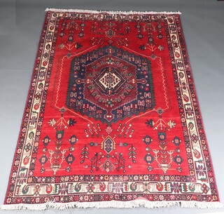A red, blue and green ground Persian rug with central medallion within a multi row border 240cm x 165cm  