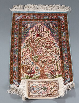 A green and floral patterned Persian silk prayer rug with tree and bird design 79cm h x 54cm d together with a white and floral patterned silk rug decorated birds and vase of flowers 30cm x 16cm 