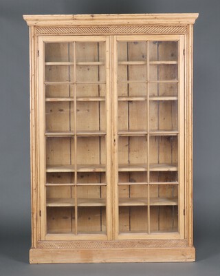 A 19th Century pine bookcase with moulded cornice, fitted shelves enclosed by astragal glazed doors, raised on a platform base 77cm h x 123cm x 37cm 