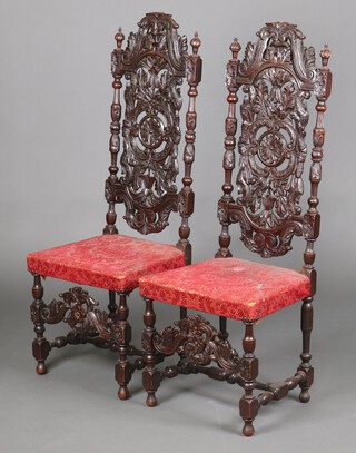 A pair of Victorian Carolean style carved oak high back chairs with pierced splat backs and upholstered seats, carved aprons, raised on turned and block supports 130cm h x 46cm w x 41cm d 
