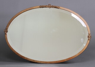 A 1920's oval bevelled plate wall mirror contained in a gilt painted metal frame with garland decoration 53cm h x 79cm w 