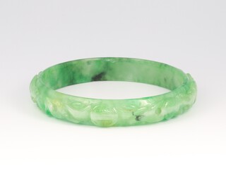 A Chinese apple green carved jade bangle decorated with characters and fish, interior diameter 6cm 