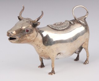 An Edwardian Georgian style silver cow creamer in the form of a cow with garnet eyes, engraved decoration and a bee to the lid, import marks London 1903, 14cm, 166 grams 