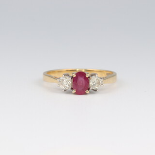 An 18ct yellow gold ruby and diamond ring, the oval ruby 0.50ct, the 2 brilliant cut diamonds together 0.50ct, size N
