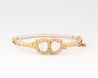 An Edwardian 14ct yellow gold moonstone and seed pearl double heart bangle, 5.5cm x 4.5cm, 11.9 grams
