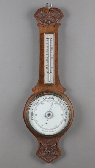 An Edwardian aneroid barometer and thermometer with porcelain dial contained in an oak wheel case 79cm 