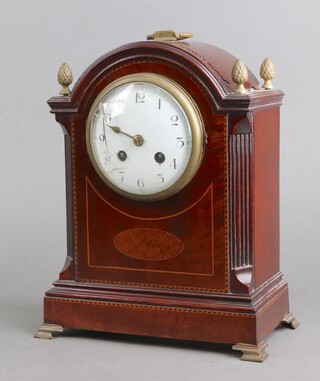 An early 20th Century French 8 day striking mantel clock with 10cm enamelled dial, Arabic numerals, contained in an arch shaped inlaid mahogany case with brass carrying handle and fluted columns to the sides 29cm h x 22cm w x 12cm d 