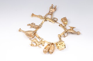 A 9ct yellow gold charm bracelet with 9 charms in total (6 9ct) including 1966 World Cup, trapeze monkey with diamond belly button and ruby eyes, magic lamp etc (2 charms 18ct, 1 charm 14ct), gross weight 62.2 grams 