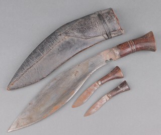 A Kukri with wooden grip together with 2 skinning knives contained in a black leather scabbard 
