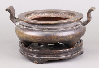A bronze tripod censer, Xuande mark, 17th/18th century the spherical body rising to a flared rim, with two outward turned handles rising from the shoulders 10cm h x 25.5cm diam across the handles, with possible matching bronze stand
