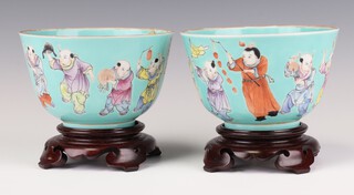 A pair of turquoise ground cups on stands, Jiaqing seal marks, late Qing dynasty, each painted to the exterior and interior with boys playing musical instruments or holding objects, 9cm h x 13cm diameter 