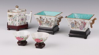A famille rose hexagonal chocolate pot, late Qing dynasty, its handle attached at a right angle to the spout painted with stylised lotus 7cm, together with a pair of famille rose square cups, late Qing dynasty, painted with scholars seated at a table 5cm and a pair of 18th century style famille rose tea bowls painted with peony, late Qing dynasty 2.5cm (5)