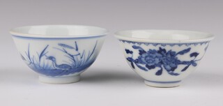 A blue and white duck and rushes cup, Guangxu mark and period, painted with one duck in flight, the other standing on a river bank; together with a blue and white cup, Guangxu mark and period, painted with peony 3.5 cm and 6.5cm diameter (2) 
