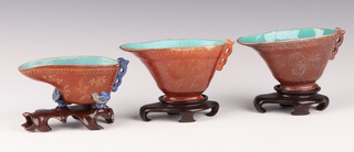 Three small coral ground and gilt ewers, late Qing dynasty, each with a pierced handle and painted with flowers, the interiors covered in a turquoise glaze, one with a blue enamel handle and three ruyi feet,  cm,   cm and   cm long (3)

