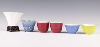 A group of six monochrome cups, late Qing dynasty, comprising a pair of ruby enamel cups, a blue and yellow octagonal cup, each with a Daoguang mark, a Dehua octagonal cup, wood stand and a blue-glazed floral cup, the largest - 8cm diameter (7)