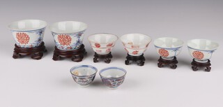 A pair of bowls and three pairs of cups, late Qing dynasty, comprising a pair of iron-red and underglaze blue floral roundel bowls, with Yongzheng marks 5cm by 8.5cm  a pair of iron-red and underglaze blue floral roundel cups, with Yongzheng marks 3cm by 5cm, a pair of underglaze blue and enamel lotus cups 4cm by 6.5cm and a pair of iron red cups painted with panels of characters 3.5cm by 6.5cm cm, (8)