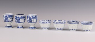 A set of three blue and white egg cups and four blue and white cups, late Qing dynasty the egg cups painted with retreats in a mountainous river landscape, the cups with a central band of rice grain pattern, painted with bands of flowers, the egg cups 7cm h x 5cm diam, the cups - 4.5cm x 5.5cm diameter (7)
  
