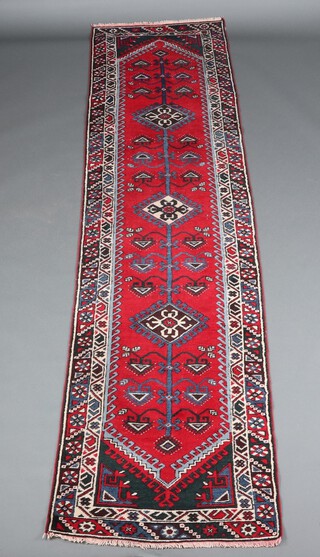 A red, blue and green Turkish runner with 3 diamonds to the centre within a multi row border 304cm x 76cm 