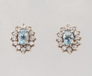 A pair of white gold, testing as 9ct, oval topaz and diamond ear studs, the topaz each 0.5ct, the 24 brilliant cut diamonds each 0.03ct, 2.6 grams 