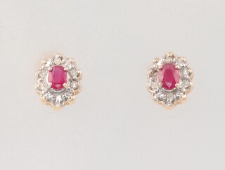 A pair of 9ct yellow gold oval ruby and diamond ear studs, 2 rubies each 0.15ct, the 11 (ex 12) diamonds each 0.01ct, 1.8 grams 