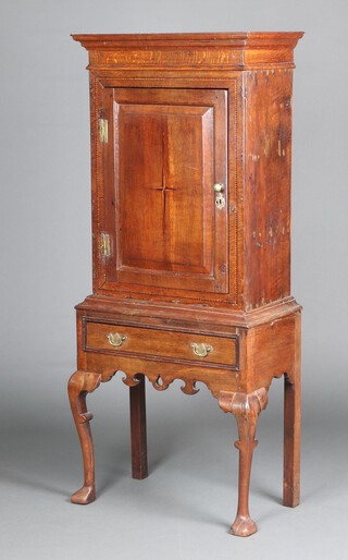 An 18th Century inlaid oak cabinet on stand with moulded cornice, fitted shelves enclosed by a panelled door inlaid a stylised cross, the associated base with pierced shaped apron and 1 long drawer, raised on cabriole supports 162cm h x 69cm w x 36cm d 