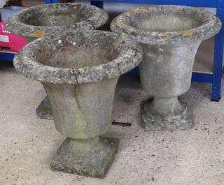 Three well weathered circular concrete garden urns, raised on square bases 48cm h (all with cracks)