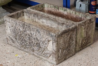 A pair of well weathered rectangular concrete garden planters with flower decoration, raised on stands, 29cm h x 58cm w x 24cm d 