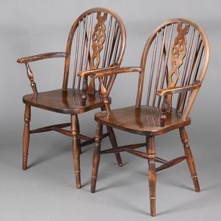 A pair of beech wheel back carver chairs, raised on turned supports 95cm h x 56cm w x 49cm d 