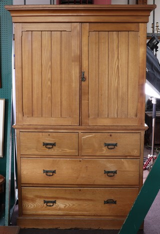 An Arts and Crafts ash linen press with moulded cornice, fitted trays above 2 short and 2 long drawers enclosed by panelled doors, raised on a platform base 205cm h x 131cm w x 60cm d