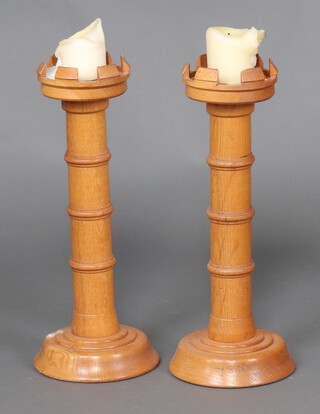 A pair of turned oak and castellated turned candlesticks 56cm h (chips to top)