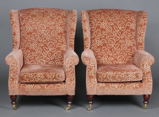A pair of Parker Knoll winged armchairs upholstered in terracotta and gold sculpted material, raised on turned supports 96cm h x 71cm w x 69cm d 