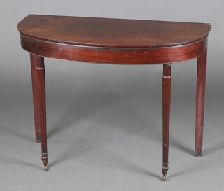 A 19th Century mahogany demi-lune table raised on turned supports with brass caps and casters 71cm h x 97cm w x 47cm d (old but treated worm in places, 2 sections of timber let in to the top, replacement back legs) 