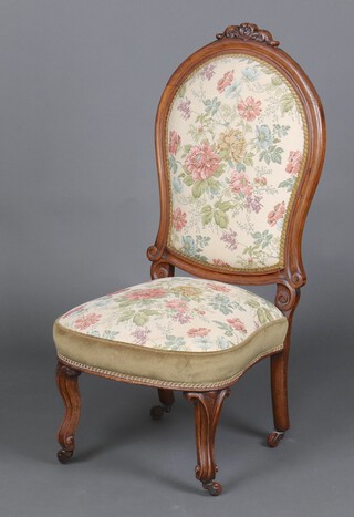 A Victorian carved walnut show frame nursing chair, upholstered in floral material 103cm h x 48cm w x 46cm d
