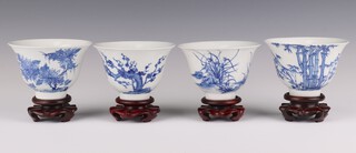 Four 20th Century Chinese bowls decorated with trees, with wooden stands 