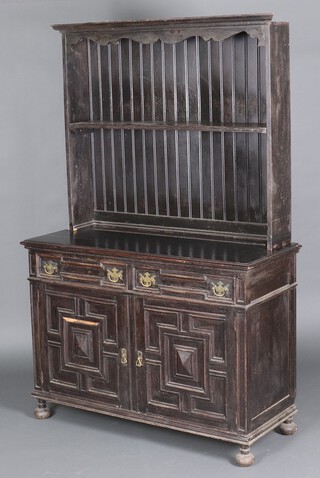James Shoolbred and Co., a Victorian Gothic style ebonised dresser, the raised back with moulded cornice, the base fitted 2 drawers above double cupboard enclosed by geometric panelled doors, on bun feet 191cm h x 121cm w x 51cm d 