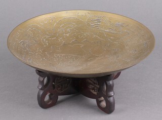 A circular Chinese engraved brass bowl on a hardwood stand 25cm