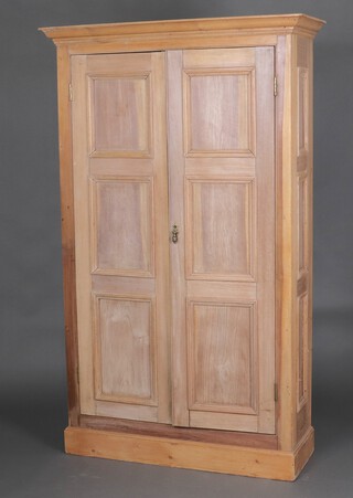 A hardwood and pine cabinet with moulded cornice and shelved interior enclosed by panelled doors, raised on a platform base 200cm h x 121cm w x 43cm d 