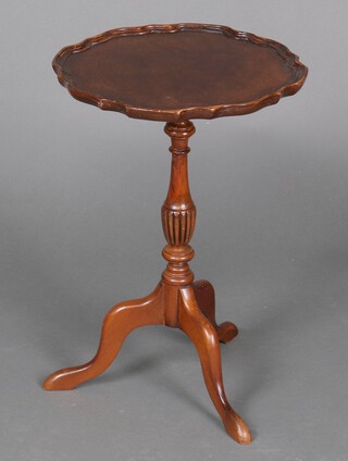A Georgian style circular mahogany wine table with pie crust edge, raised on a pillar and tripod base 50cm h x 35cm diam.