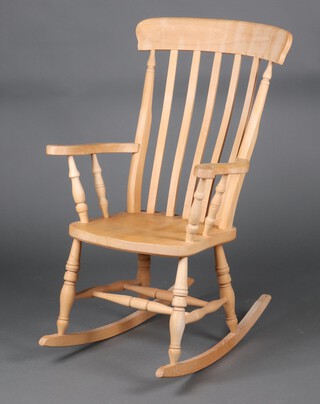 A 19th Century style beech Windsor stick and rail back rocking chair with solid seat, raised on turned supports 117cm h x 66cm w x 76cm d (sun bleached)