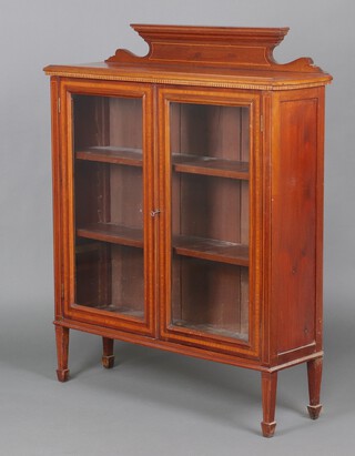 An Edwardian inlaid mahogany display cabinet with raised back, fitted shelves enclosed by glazed panelled doors, raised on square tapered supports 132cm h x 106cm w x 31cm d 