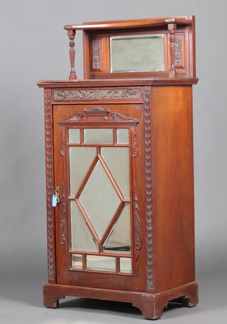 An Edwardian carved walnut music cabinet, the raised back fitted a bevelled plate mirror, the shelved cupboard enclosed by a bevelled plate mirror panelled door 130cm h x 62cm w x 40cm d 