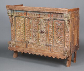 An Indian carved hardwood cabinet with arcaded shaped and stud carved cornice, enclosed by a deeply carved panelled door, having iron brackets to the sides, supported by 2 elephants, raised on shaped supports 104cm h x 122cm w x 56cm d 