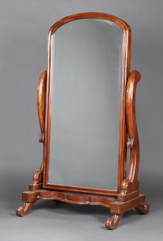 A Victorian arch plate cheval mirror contained in a mahogany swing frame, the base of serpentine outline, raised on scroll supports 152cm x 80cm x 62cm 