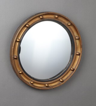 A circular Regency style convex plate wall mirror contained in a wooden and gilt painted ball studded frame 45cm diam. 