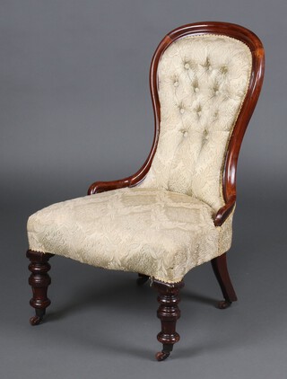 A Victorian mahogany show frame nursing chair upholstered in gold sculpted buttoned material, the seat of serpentine outline, raised on turned supports 88cm h x 55cm w 