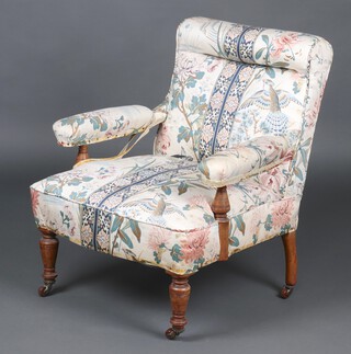 A Victorian Howard style open arm chair upholstered in Sanderson type material, raised on turned supports with ceramic casters 78cm h x 64cm w x 60cm d 