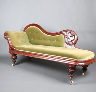 A Victorian carved mahogany show frame chaise longue, the arm with pierced and carved eagles head, upholstered in green buttoned material raised on turned supports with ceramic casters 80cm h x 182cm l x 55cm d 